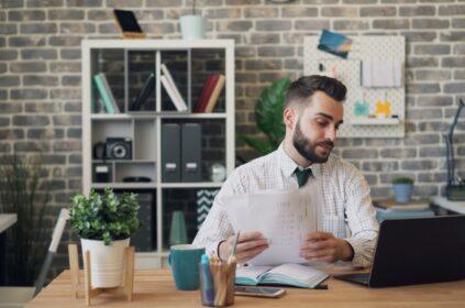 a man sitting at a desk with a laptop and papers