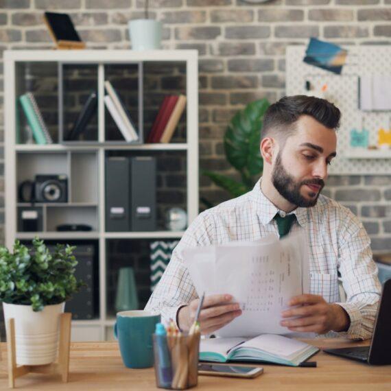 a man sitting at a desk with a laptop and papers