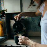 woman in white t-shirt holding black ceramic mug