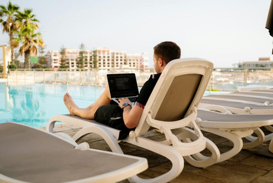 man on sun lounger using laptop