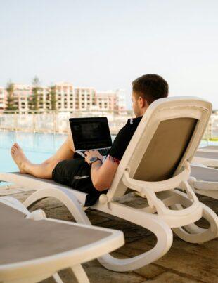 man on sun lounger using laptop