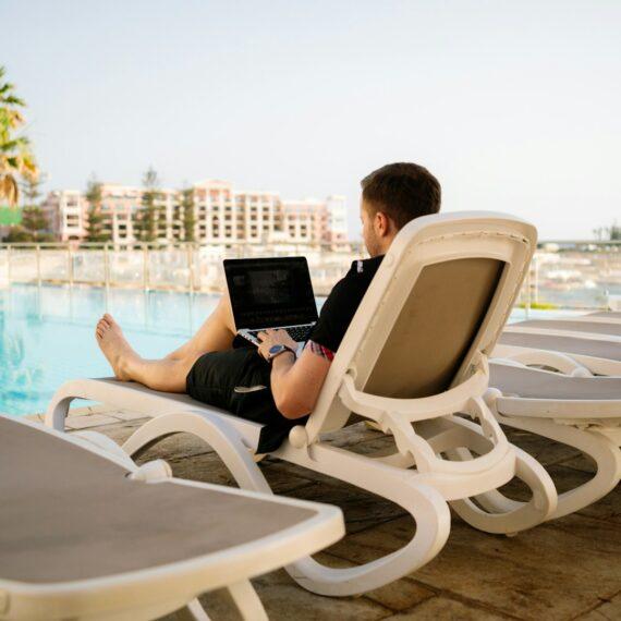 man on sun lounger using laptop