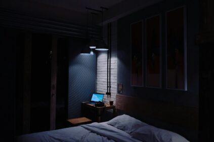 turned-on laptop computer on top of side table inside bedroom