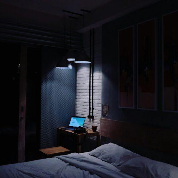 turned-on laptop computer on top of side table inside bedroom